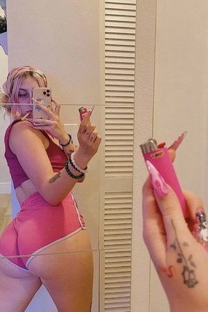 Woman in pink outfit taking mirror selfie indoors.