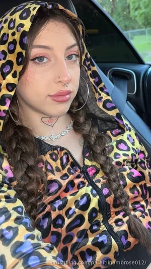 Woman with braided hair in leopard print hoodie, sitting in car, wearing jewelry and nose ring.
