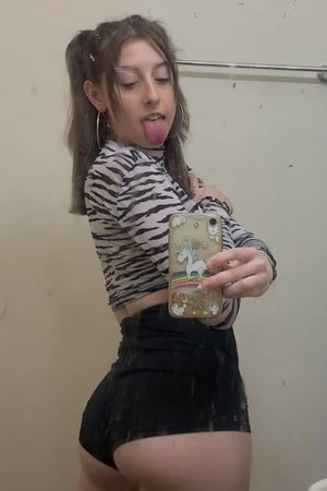 Woman with pigtails in zebra top taking mirror selfie indoors.