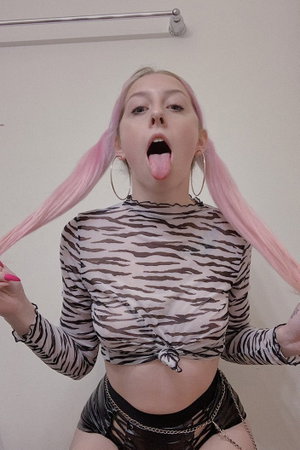 Woman with pink pigtails wearing zebra top and black bottoms indoors.