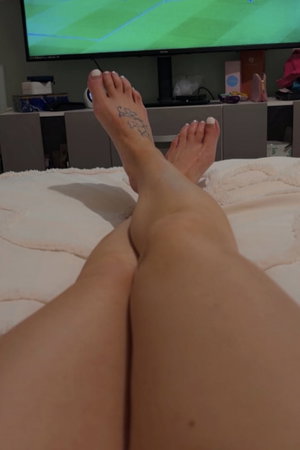 Woman's legs and tattooed feet on bed.