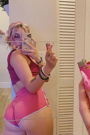 Woman in pink outfit taking mirror selfie indoors.