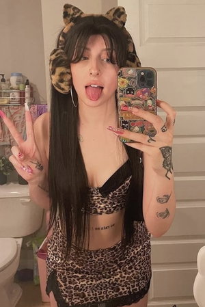 Woman taking mirror selfie in bathroom wearing leopard print outfit.
