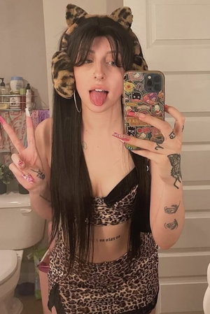Dark haired woman in leopard print taking bathroom selfie.