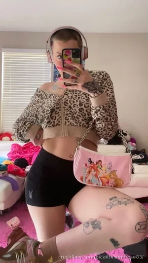 Woman in leopard crop top and black shorts, tattoos, pink rug, mirror selfie.