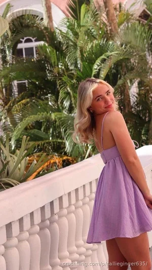 Woman in purple dress posing on balcony with tropical plants behind.