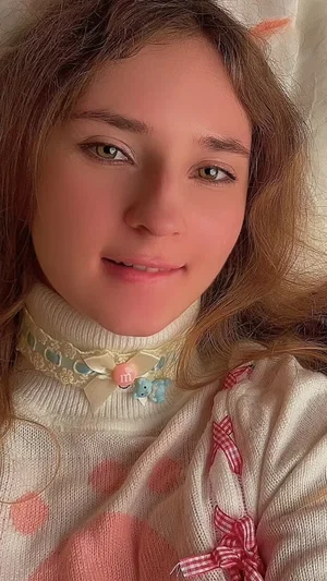 Woman with brown hair in polka dot sweater and choker taking selfie.