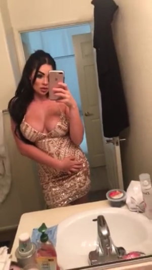 Curvy woman in sequined dress taking mirror selfie in bathroom.