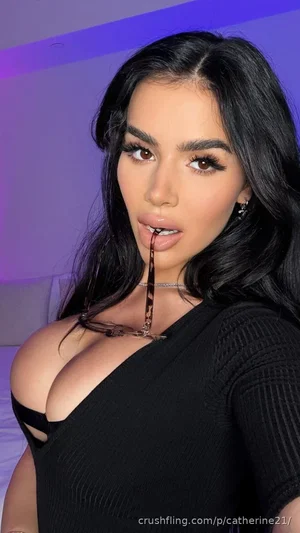 Woman with long black hair in black top, posing indoors with purple lighting.