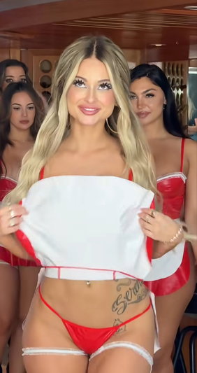 Woman with blonde hair in red lingerie holding white top, surrounded by others in similar outfits