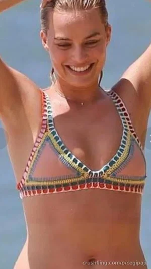 Woman in colorful bikini top smiling at beach, arms raised, sunny outdoor setting.