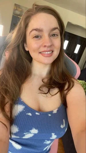 Brunette woman in blue tank top in gaming chair.