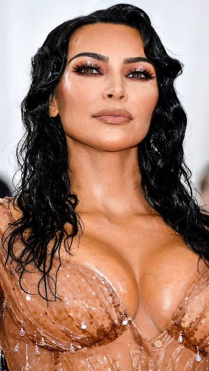 Dark-haired woman in sheer sequined top with glam makeup.