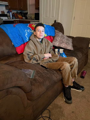 Man in brown hoodie seated on couch in living room