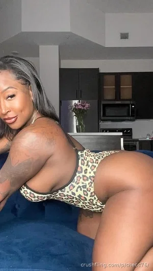 Woman with gray hair in leopard print lingerie posing on blue couch in kitchen.