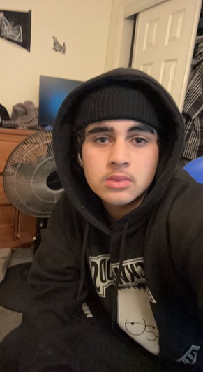 Young man in black hoodie and beanie indoors.