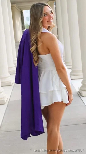Woman in white dress and purple jacket posing outdoors near columns.