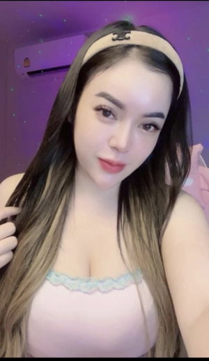 Asian woman with long hair in pink lace top, purple room.