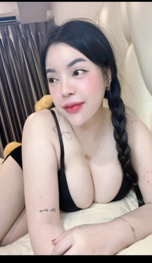 Asian woman with braids in black bra on bed.