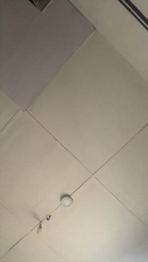 Indoor ceiling with white panels and lights.