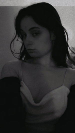 Woman with dark hair in white top indoors.