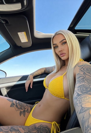 Woman with blonde hair and tattoos wears yellow bikini, sitting in car.