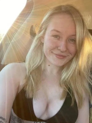 Blonde woman in brown top taking selfie indoors.