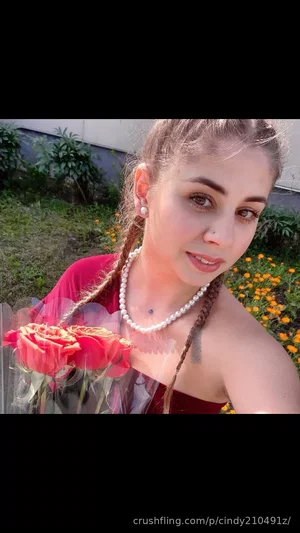 Woman with braided hair in red top holding roses outdoors.