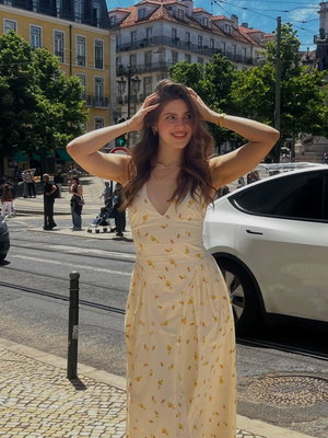 Woman in floral dress posing on city street.