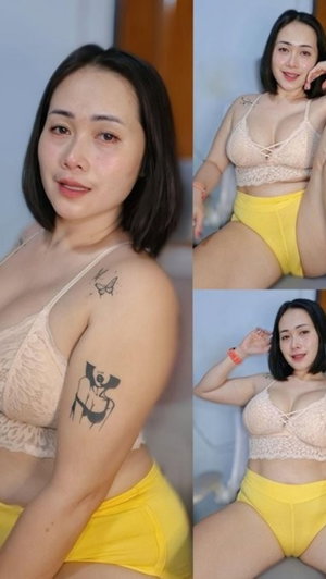 Woman with short dark hair in beige lace bra and yellow underwear, posing indoors.