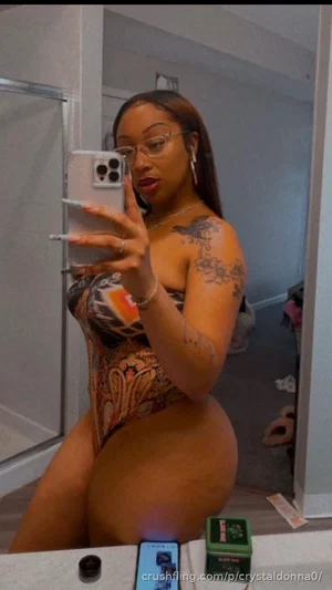 Woman with tattoos in colorful bodysuit taking mirror selfie in bathroom.