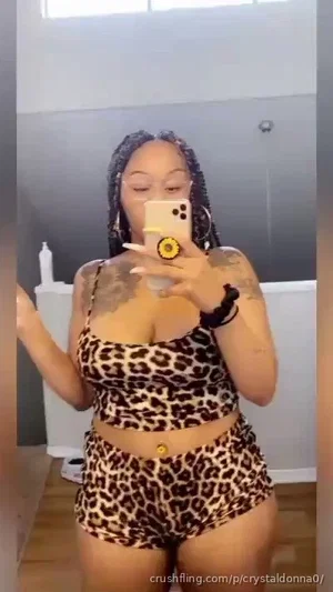 Woman in leopard print top and shorts takes mirror selfie in bathroom.