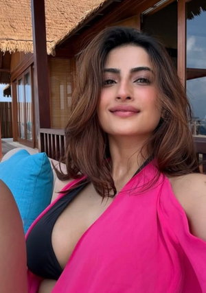 Woman with brown hair in pink top taking outdoor selfie.