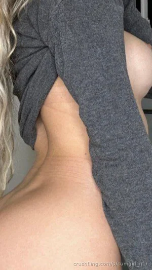 Woman with blonde hair wearing gray top with back cutout, showing bare skin.