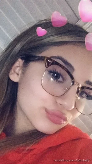 Woman with glasses and pink heart filters, wearing red top, indoor setting.