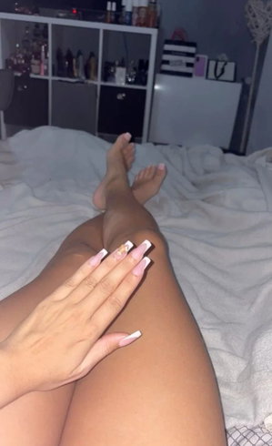 Woman's legs and hands on bed in bedroom.