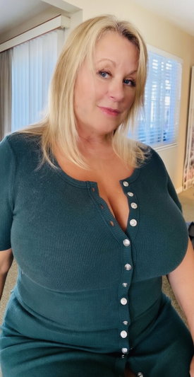 Blonde woman in green top posing indoors.