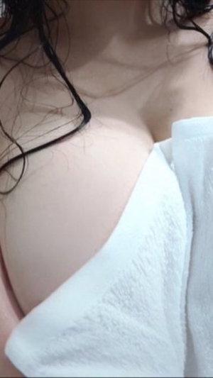 Woman with dark curly hair in white off-shoulder top.