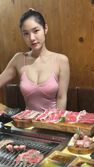Asian woman in pink camisole at Korean BBQ restaurant.