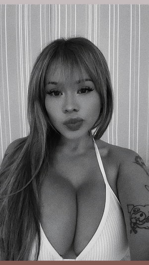 Woman with long hair and tattoo wears white top, standing indoors.