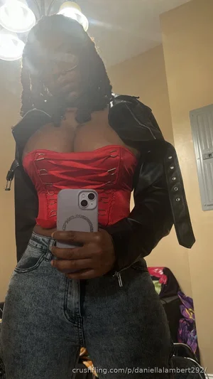 Woman in red corset and black jacket, holding phone, taking mirror selfie indoors.