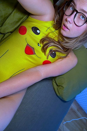 Woman with glasses in Pikachu shirt on bed.