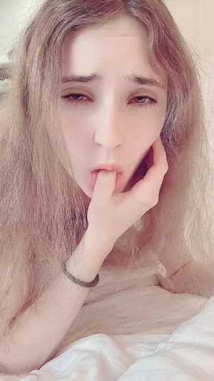 Woman with long light brown hair lying in bed.