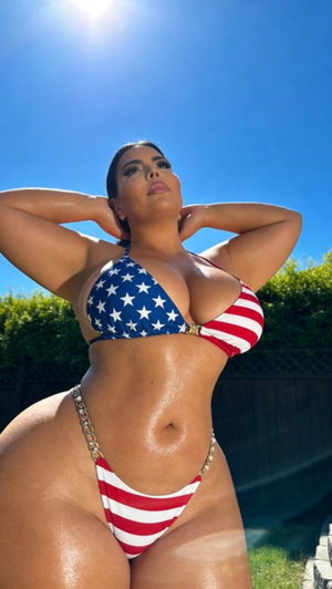 Curvy woman in stars and stripes bikini posing outdoors.