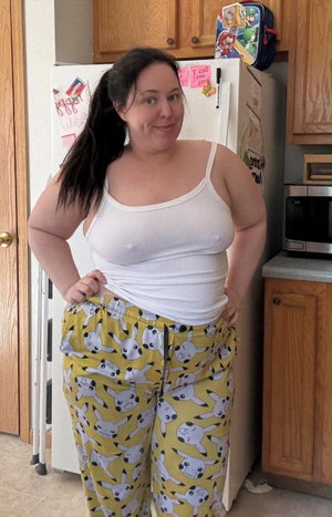 Woman in white tank top and yellow Pikachu pants standing in kitchen.