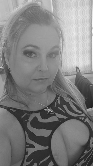 Blonde woman in patterned top taking selfie indoors.