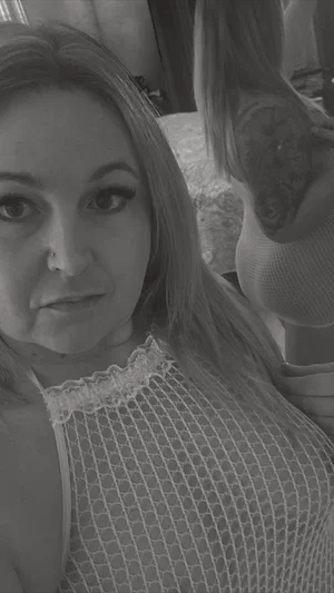 Woman with long hair in sheer mesh top, holding phone, indoors.