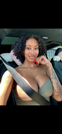 Woman with curly hair in green top taking car selfie.