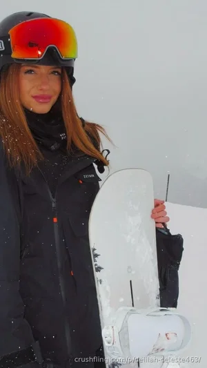 Woman in black ski gear holding snowboard on snowy slope.