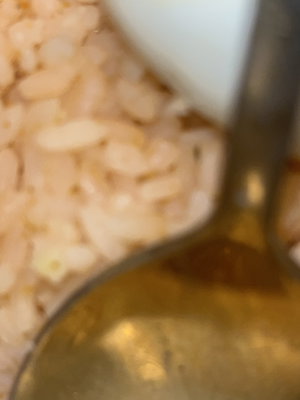 Close-up of cooked rice with a spoon in a bowl.